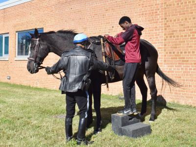 Student getting instruction from the US Parks Police officer on how to mount the horse.