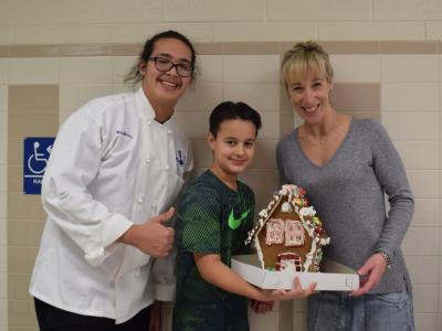 Young people and a parent with their gingerbread house