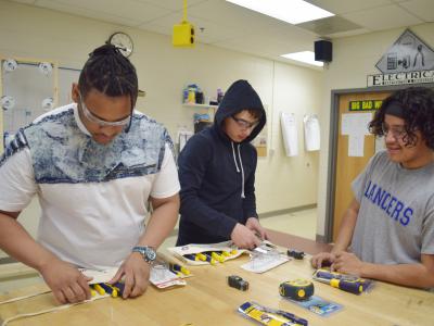Students with tools used by electricians. 