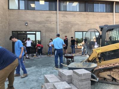 Pallets of pavers and students preparing for installation. 