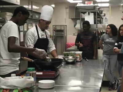 Students watch Chef Jeff from JWU prepare pasta primavera.